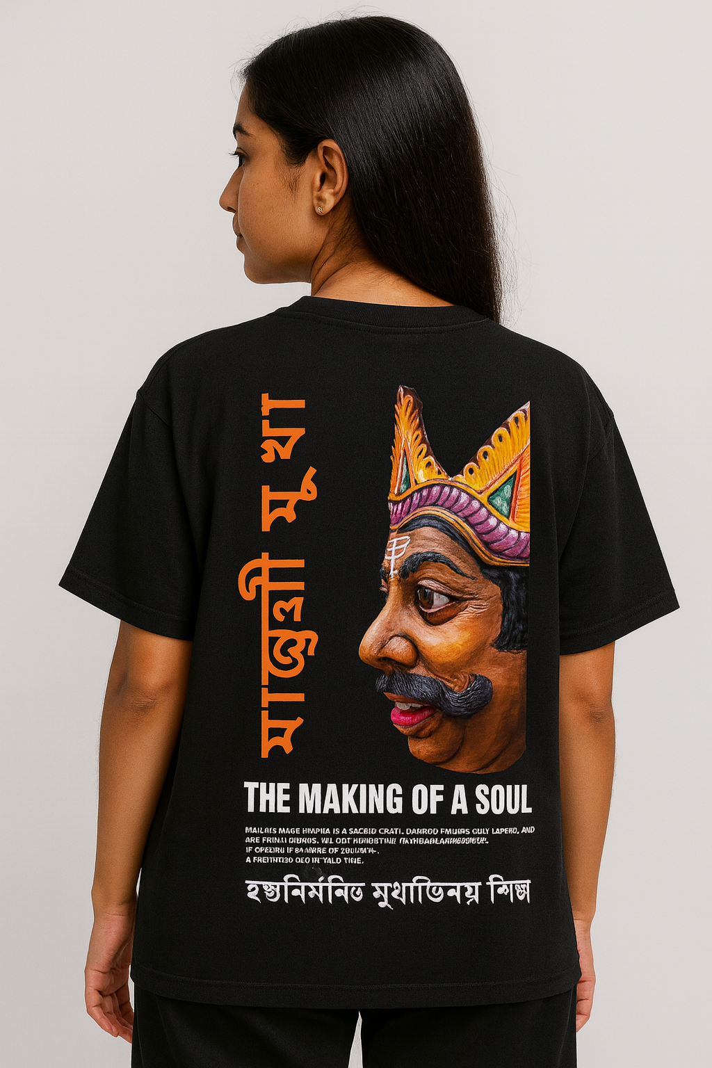 Female model wearing black oversized Majuli mask-art T-shirt with Assamese typography — WE TEES cultural streetwear.