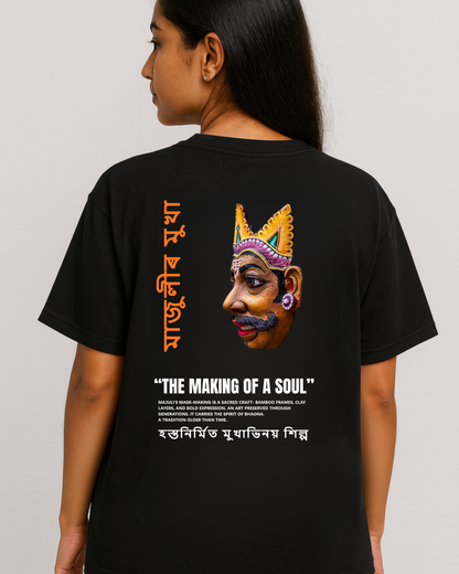 Assam Majuli mask-making artwork T-shirt — Assamese text and Bhaona mask graphic on black oversized tee (female model).