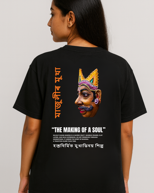 Assam Majuli mask-making artwork T-shirt — Assamese text and Bhaona mask graphic on black oversized tee (female model).